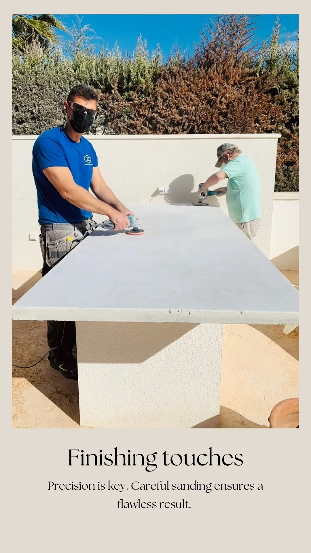 Two craftspeople sanding an outdoor kitchen worktop