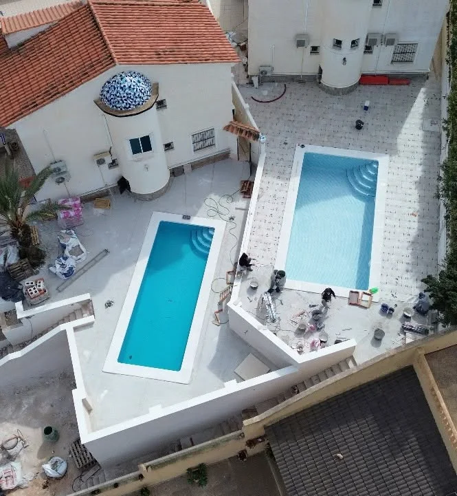 Aerial view of two pool installations with terrace work in progress